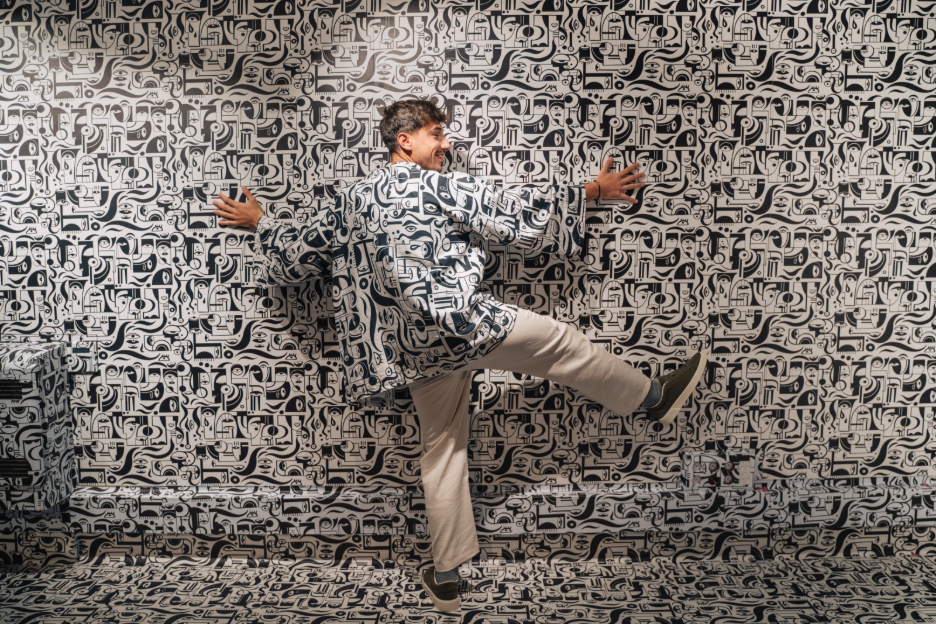 Visitor posing playfully in a black-and-white patterned IKONO room while wearing a matching patterned robe.